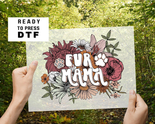 A direct to film transfer that has a floral background with the words Fur Mama overlayed on top. Fur Mama is written in a white colored retro font. The DTF transfer is a cold peel ready to press transfer.