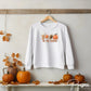 A picture of a white sweatshirt with cute pictures of coffee, leaves, footballs and pumpkins and the words Tis The Season. DTF transfers, DIY , Make your own shirt